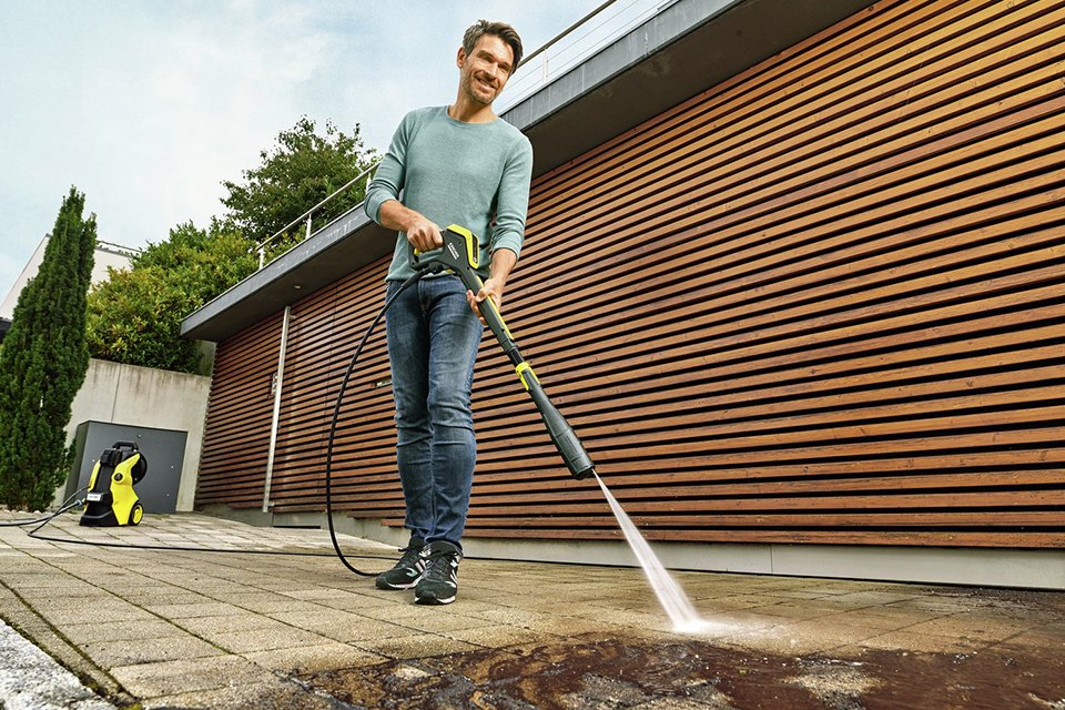A person jet washing their patio with a pressure washer.